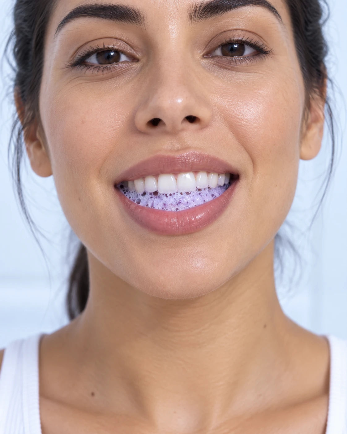 Illustrative use: pale purple foam visible around the teeth