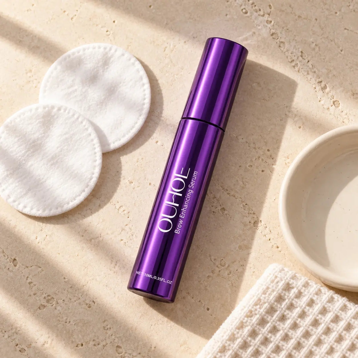 Purple serum beside a washcloth and cotton pads